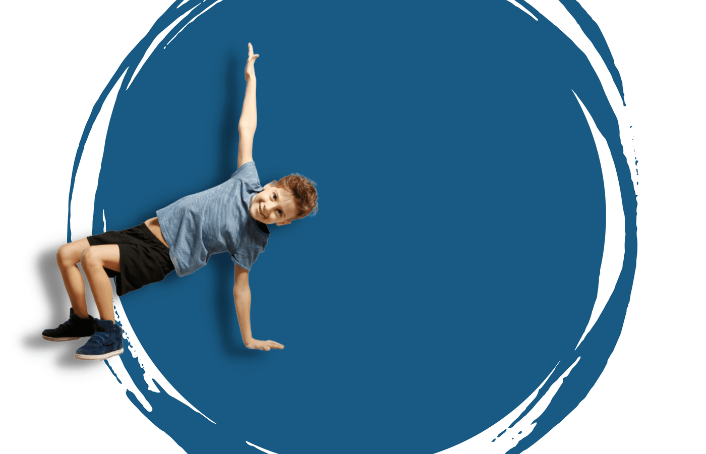 A young male dancer, wearing a grey t-shirt and black shorts, posed with both feet and one arm on the ground, the other arm reaching up. The background has a light blue/grey large paint splat over a light grey backdrop.